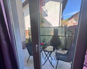 a woman sitting on a balcony with a table and chairs at MM Apartman in Foča