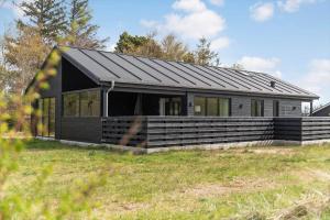 a house with a black roof on a field at HS018-Henne-Hennebysvej-8 in Henne Strand