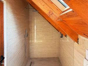 a shower stall in a bathroom with a wooden ceiling at Vila Shkalla in Theth