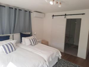 a bedroom with two white beds and a glass shower at Berg and Dal in Paarl