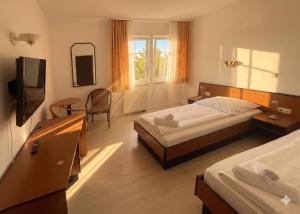 a hotel room with two beds and a television at Malerwinkel Hotel in Wertheim