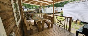 a wooden porch with a picnic table on a deck at A 15 minutes de l'océan, Mimizan plage in Aureilhan