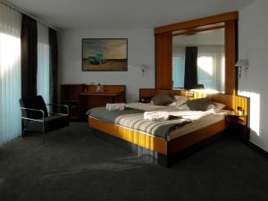 a bedroom with a large bed and a chair at Malerwinkel Hotel in Wertheim