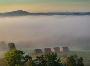 a group of huts in the fog next to a lake at Widokowe Stodoły Bieszczady-domy jacuzzi i widokiem połonin in Lesko