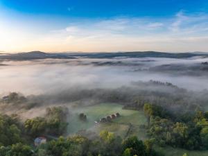 an aerial view of a foggy field with a house in the middle at Widokowe Stodoły Bieszczady-domy jacuzzi i widokiem połonin in Lesko