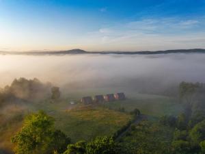 a foggy view of a field with trees and buildings at Widokowe Stodoły Bieszczady-domy jacuzzi i widokiem połonin in Lesko +111 photos