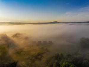 an aerial view of a foggy field with trees at Widokowe Stodoły Bieszczady-domy jacuzzi i widokiem połonin in Lesko