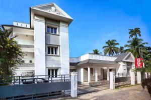 a white building with palm trees in front of it at RAGAM RESORT in Alleppey