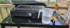 a grill sitting on a table with a cup of water at A 15 minutes de l'océan, Mimizan plage in Aureilhan