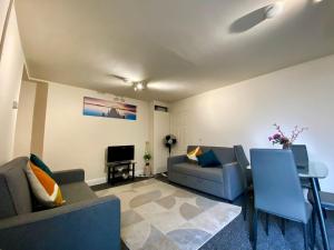 a living room with two couches and a table at Modern 2 bed ground floor flat in Watford