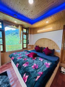 a bedroom with a large bed with purple and red pillows at The Midhimalayan Jibhi in Jibhi