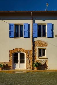 una casa bianca con persiane blu e due finestre di Podere Demetra a Novi Ligure