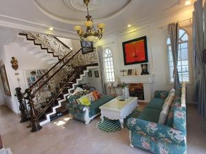 a living room with a staircase and a couch at Green Hillside Villa Hue in Hue