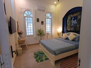 a bedroom with a bed with a blue headboard and two windows at Green Hillside Villa Hue in Hue