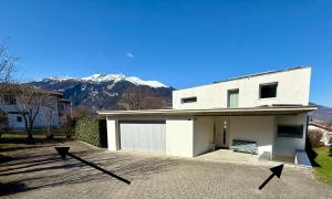 a white house with mountains in the background at Ferienwohnung Biendi in Trimmis