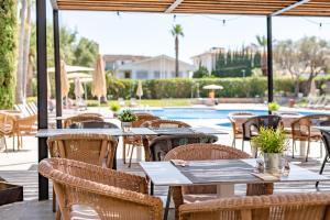 an outdoor patio with tables and chairs and a pool at Hotel Eu Bahia Pollença in Port de Pollensa