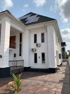 a white house with a solar roof on it at King Arthur Apartment in Akwa