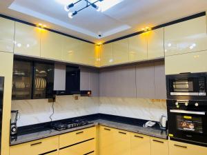 a kitchen with yellow cabinets and black counter tops at King Arthur Apartment in Akwa