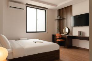 a bedroom with a bed and a desk and a television at V Living - Downtown Saigon Stay with Free Laundry in Ho Chi Minh City