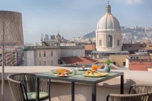 a table with two plates of food on a balcony at UNA Hotels Napoli in Naples