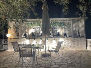 a table with chairs and an umbrella on a patio at Hotel Valerios in Kriopigi