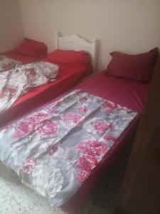 a bedroom with two beds with red sheets and flowers at iomnium in Tigzirt