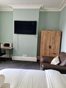 a living room with a couch and a flat screen tv at Grange House Budget Rooms in Leeds