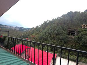 a balcony with a red bed on top of a mountain at Pinewood View Homestay in Shimla