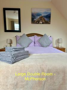 a bedroom with a large bed with purple sheets and pillows at Feochan Portree in Portree