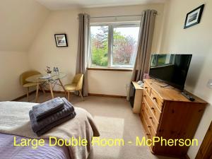 a bedroom with a bed and a tv and a table at Feochan Portree in Portree