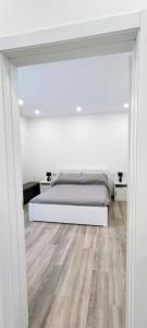 a white bedroom with a bed and a wooden floor at Chez Romeo in Ravenna +4 photos