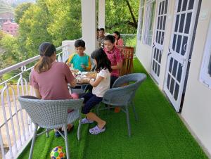 a group of children sitting at a table on a porch at Mohija Homestay in Kandāghāt