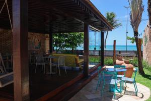 a deck with tables and chairs and a view of the ocean at Hotel Areias Belas in Maragogi