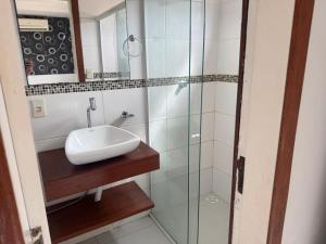 a bathroom with a sink and a glass shower at Apartamento 70 metros do mar in Florianópolis