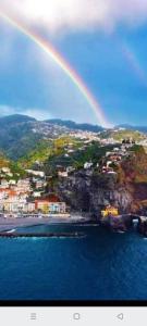 a rainbow over a town with a beach and the ocean at Arco-Íris in Ponta do Sol