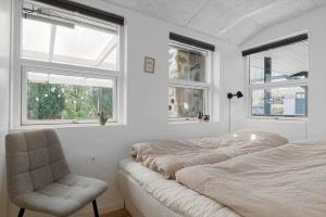 a bedroom with two beds and a chair and windows at OH585-Hadsund-Brondbaekken-34 in Øster Hurup