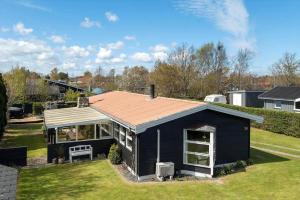 a black house with a roof on a yard at OH585-Hadsund-Brondbaekken-34 in Øster Hurup