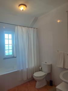 a white bathroom with a toilet and a window at Alojamento Local Velas Balcony in Velas +15 photos