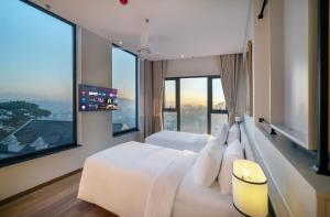 a bedroom with a white bed and large windows at Soluna Dalat Hotel in Da Lat