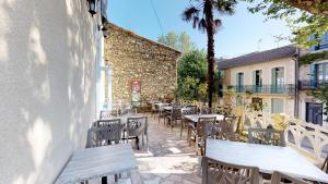 a patio with tables and chairs and a building at Hotel restaurant LAISSAC SPEISER in Olargues