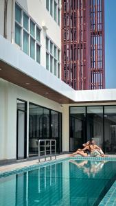 a man laying on the edge of a swimming pool at ST Central Hotel, Pakse in Pakse