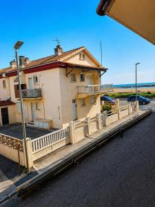 a building with a fence next to a parking lot at Studio cosy Valras, plage à 20 m in Valras-Plage