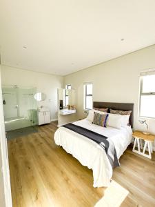 a white bedroom with a large bed and wooden floors at Bluebay Villa in Britannia Bay +51 photos