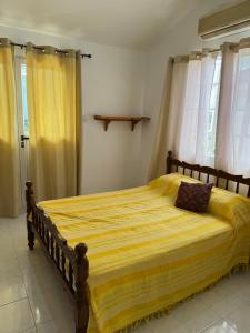 a bedroom with a large bed with yellow sheets at Coco villa in Flic-en-Flac