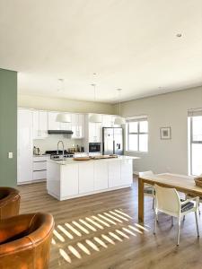 a kitchen with white cabinets and a wooden table at Bluebay Villa in Britannia Bay