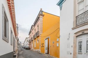 an alley with yellow and white buildings on a street at HI Tavira – Pousada de Juventude in Tavira