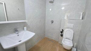 a white bathroom with a sink and a toilet at Hotel Reci in Peshkopi