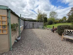 a gravel driveway next to a house with a bench at Willows Cottage in Pitlochry