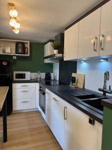 a kitchen with white cabinets and black counter tops at S'Nekel Hisel - Gîte à Offwiller in Offwiller