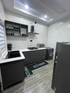 a kitchen with black cabinets and a sink and a stove at Kennys place in Isaga-Abosule